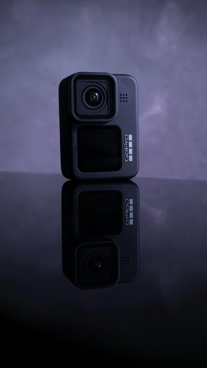 Close-up of a GoPro camera on a black reflective surface, showcasing its design.