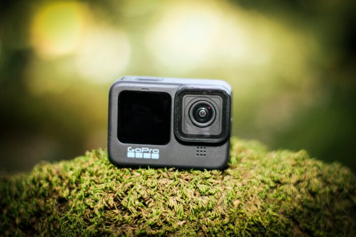 A GoPro camera placed on lush moss, captured in vibrant natural lighting outdoors.